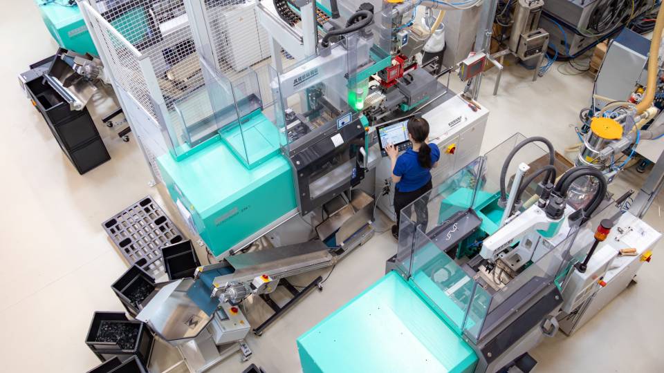 Mitarbeiterin arbeitet an Spritzgussmaschine